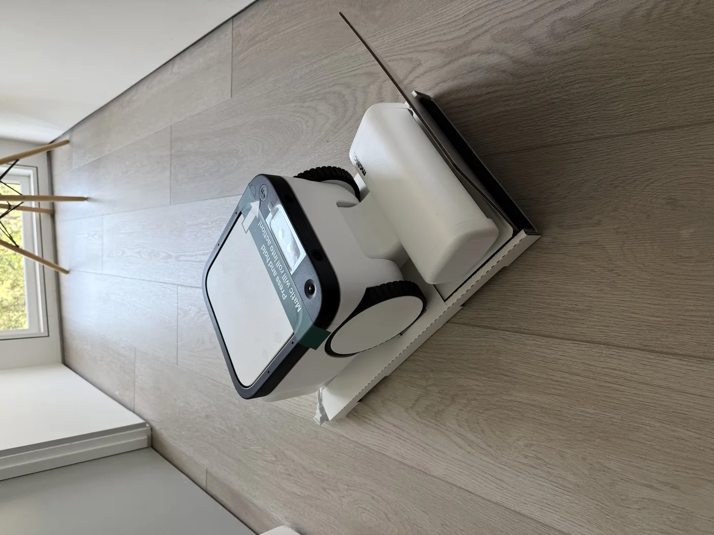Matic robot vacuum out of box on hardwood floor — tall square profile with front camera array visible
